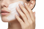 Woman applying white cream to her cheek