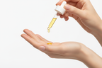 Golden serum dripping from a dropper onto an open palm